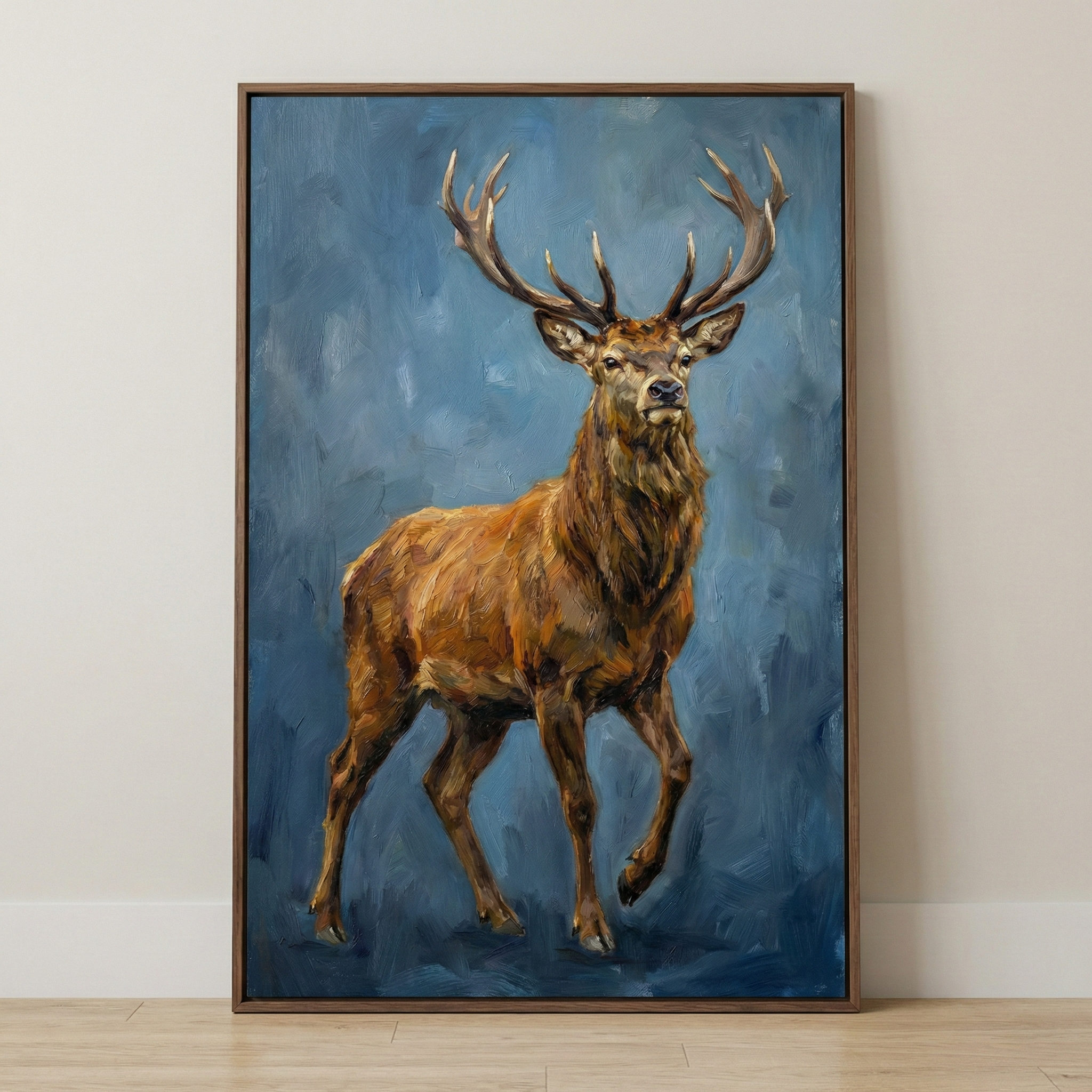 An impressionistic artistic depiction of a large deer with prominent antlers, standing against a mottled blue, textured background. The artwork, shown in shades of gold and brown with visible brushwork, is in a thin wooden frame and leaning against a neutral wall above a light wood floor.