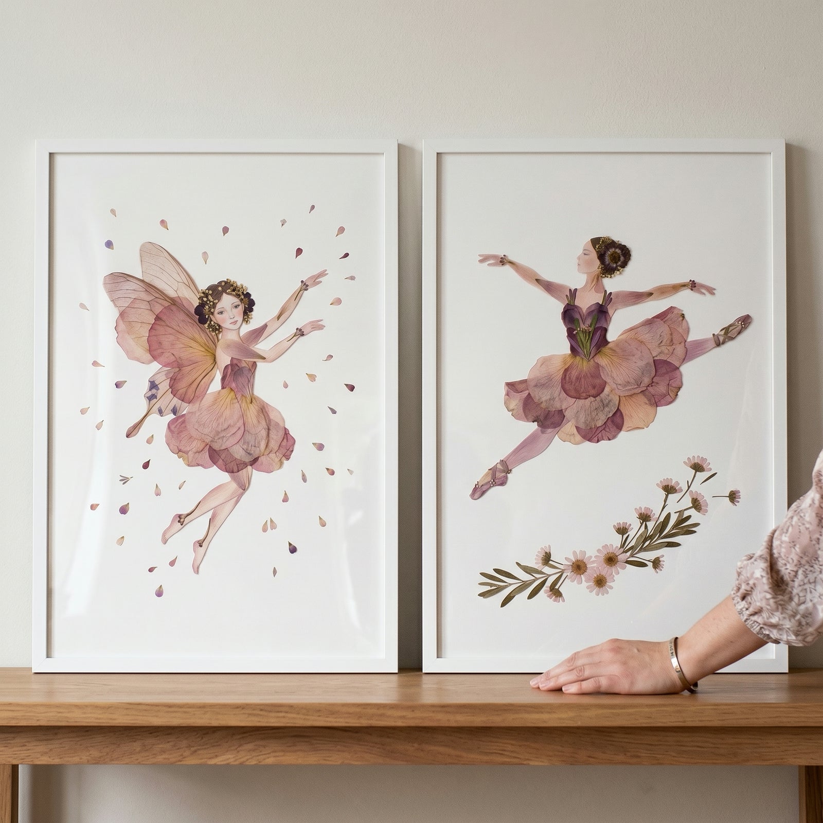 Mauve dried petal girl wall art set of 2 in white frames featuring a winged fairy and a leaping ballerina on a wood shelf.