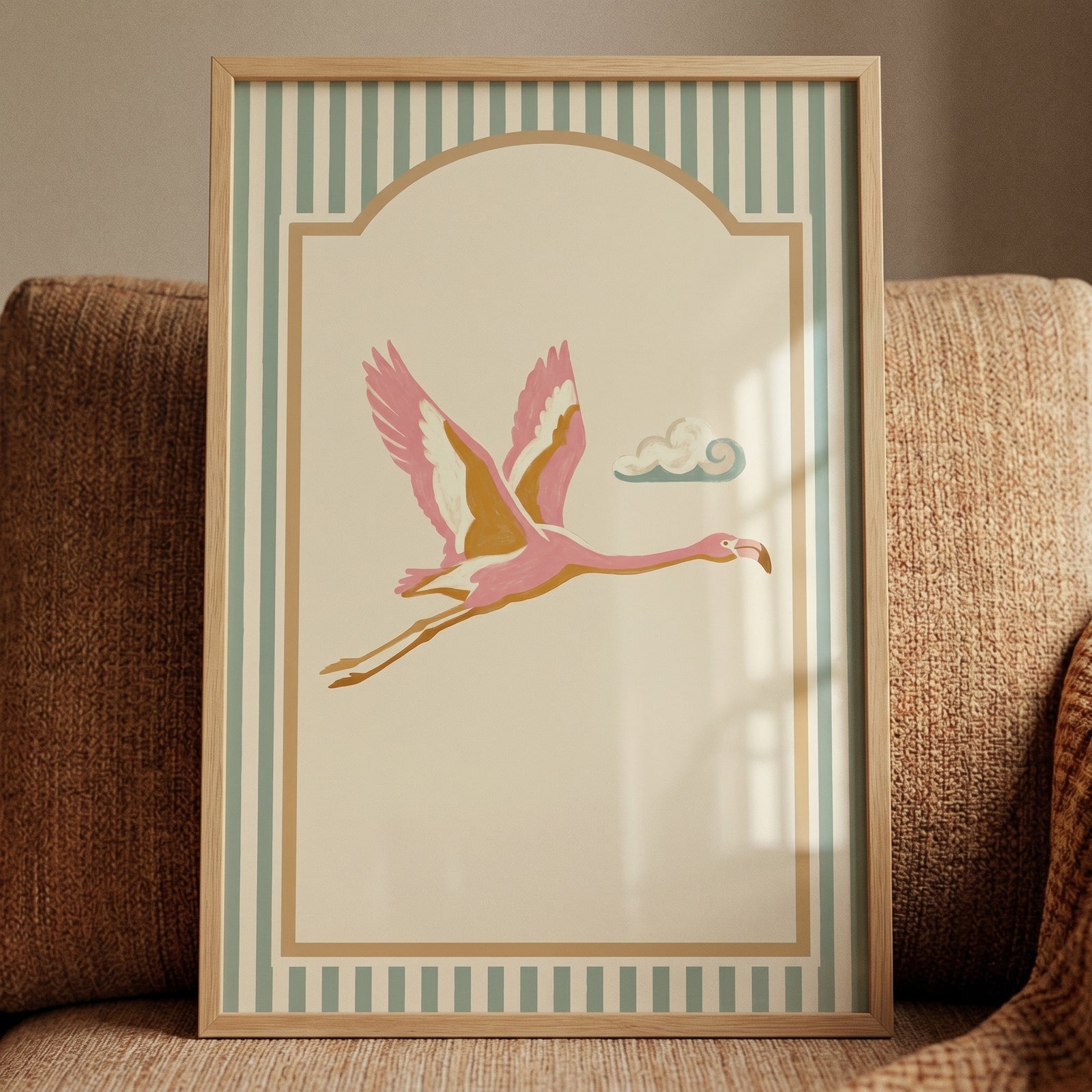 Framed mid century pink flamingo wall art with a flying bird on a cream background with a teal striped border.