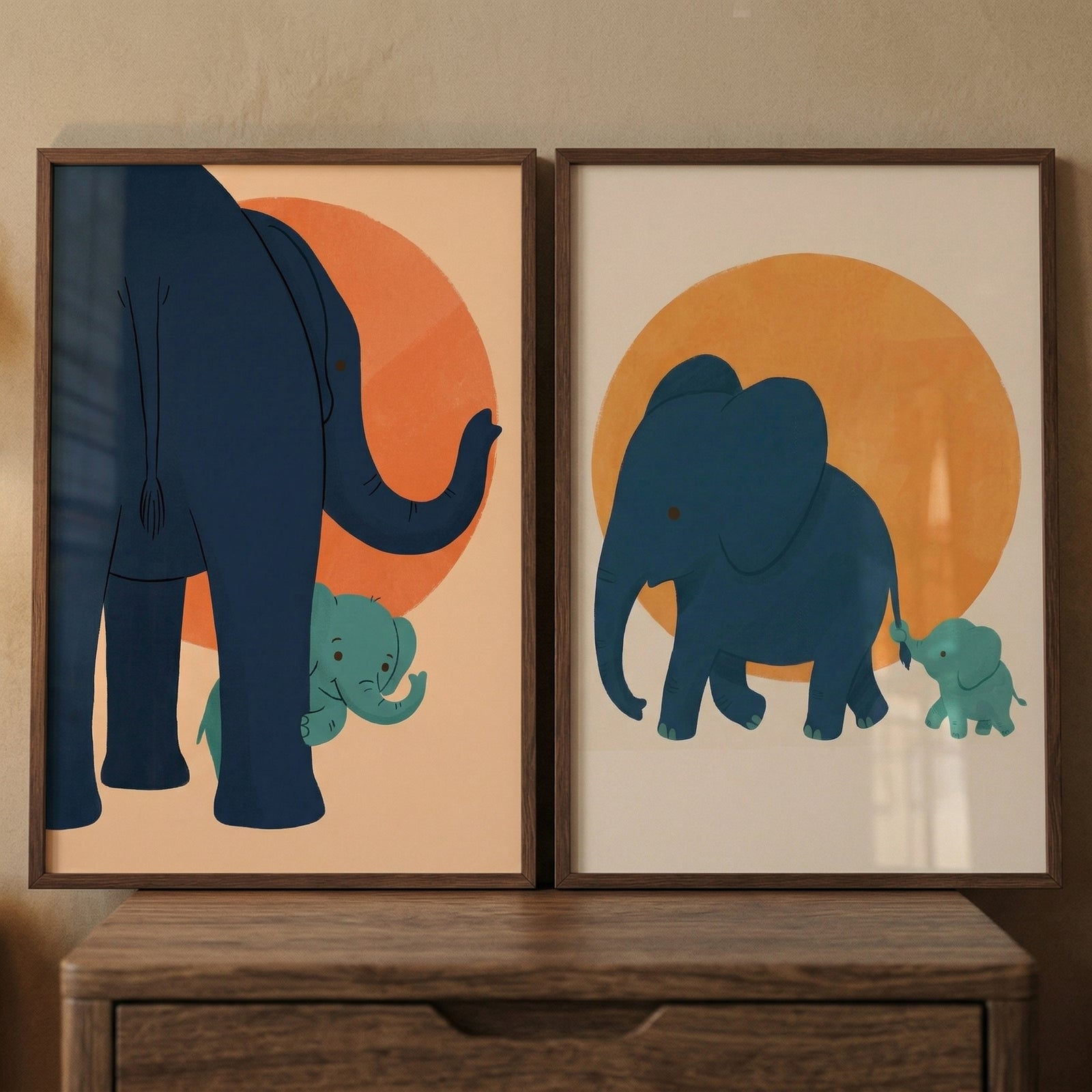 This set of two framed wall decor pieces features minimalist, cartoon-style illustrations of elephants. Each frame showcases a large dark blue elephant and a smaller light turquoise baby elephant set against a solid-colored background with a large, centered circular shape representing a sun.
