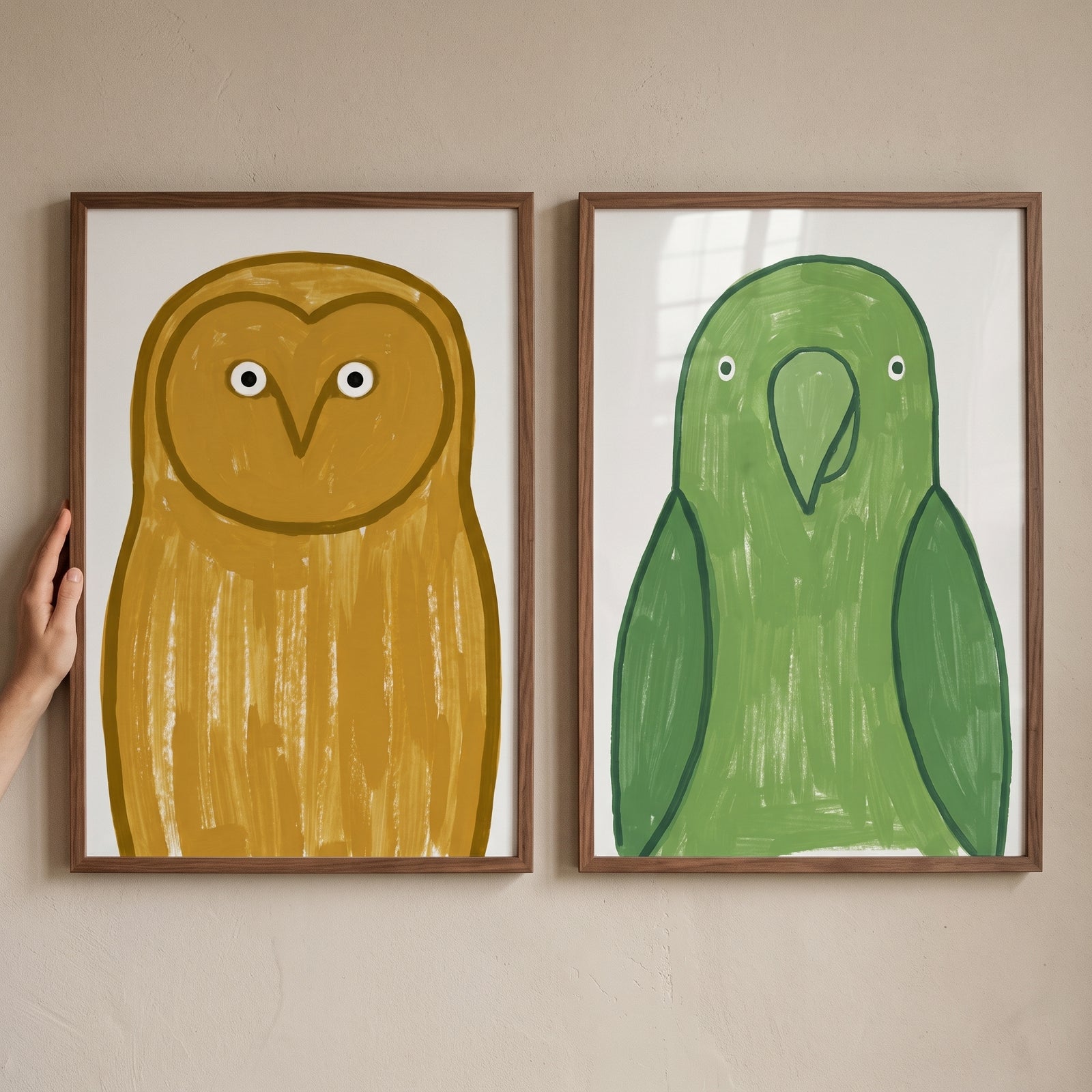 Minimalist earth tone birds artwork set of 2 featuring an ochre owl and green parrot in wood frames against a beige wall.