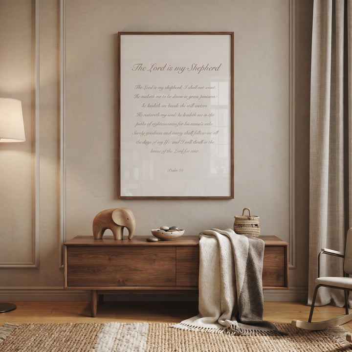 Minimalist neutral psalm 23 wall art hangs above a wooden sideboard with a small elephant and cozy blanket.