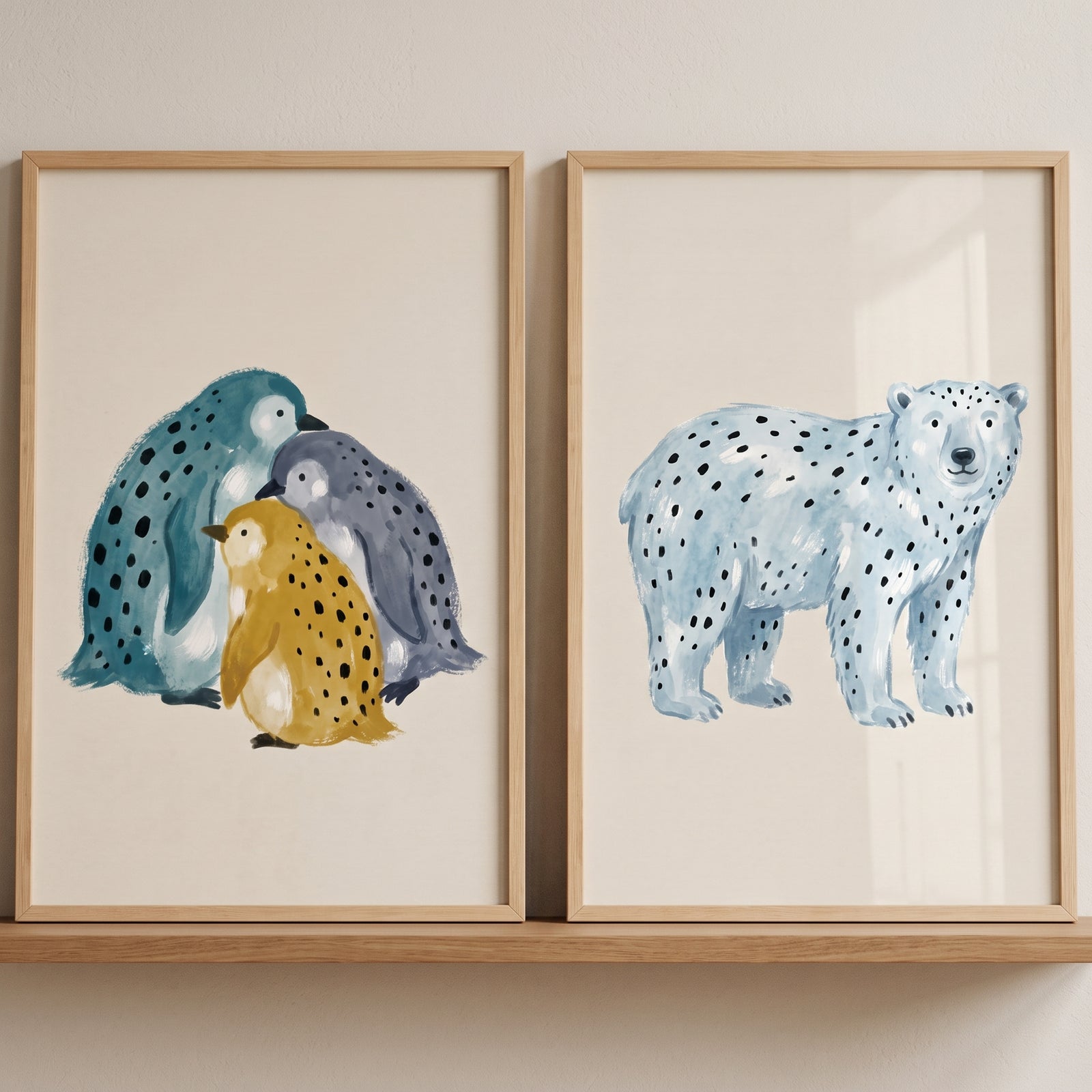 Minimalist spotted winter animal wall art set of 2 with stylized penguins and a polar bear in wood frames on a shelf.