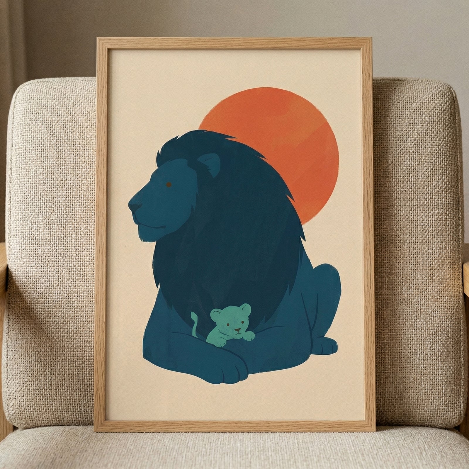 Framed illustration of a dark blue lion resting with a small cub nestled between its front paws against a warm red sun. The artwork leans on a textured beige chair creating a soft cozy focal point suitable for a nursery or child’s room.