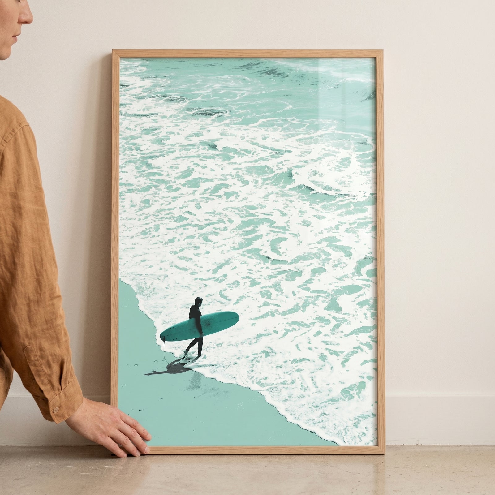 A person walks with a surfboard on a beach by foamy waves in this minimalist teal ocean surfer wall art.