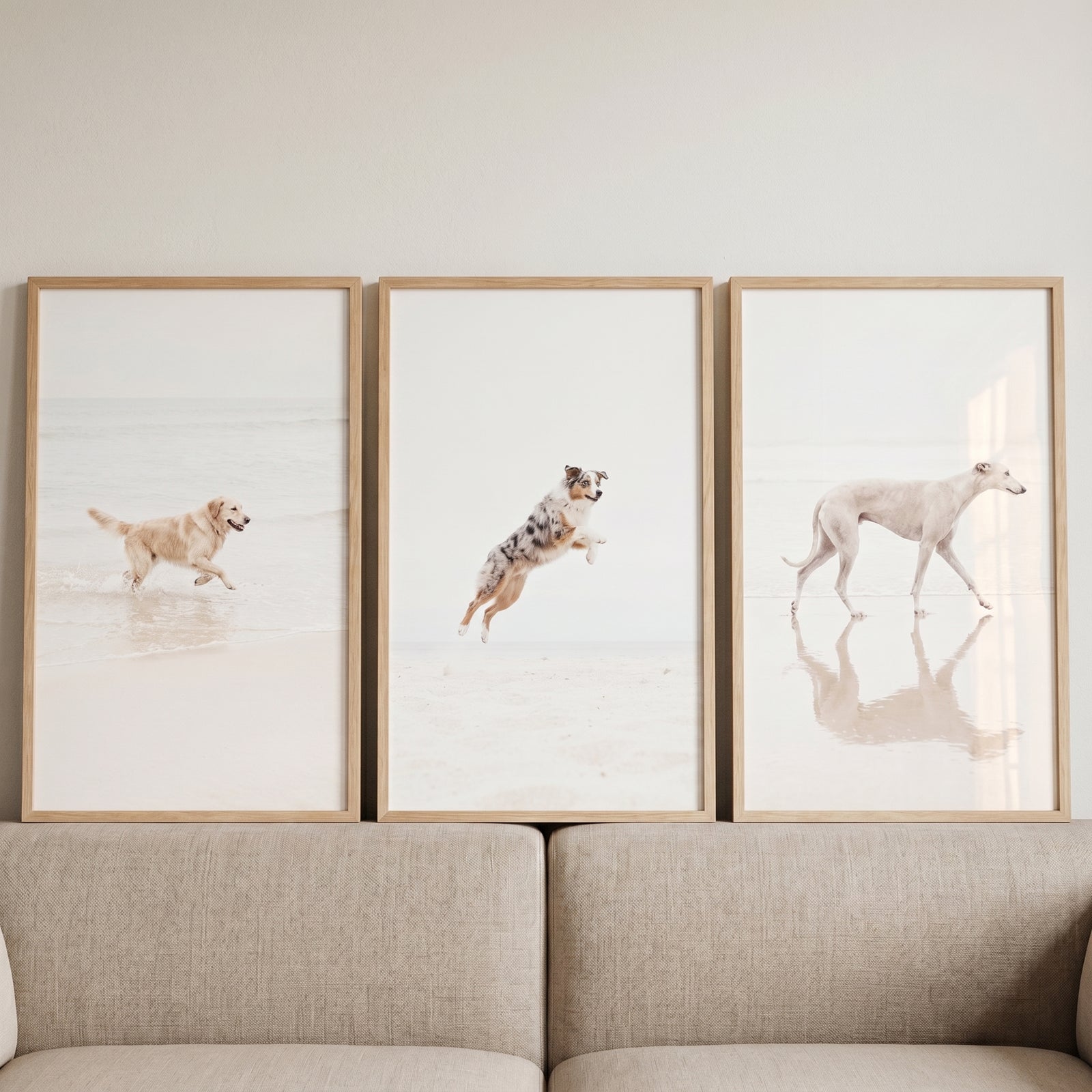 Minimalist white beach dog wall art set of 3 featuring dogs running and jumping, hung above a neutral sofa.