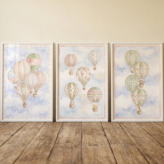 Misty hot air balloon wall art set of 3 featuring pastel patterned balloons and animals against a soft cloudy blue sky.