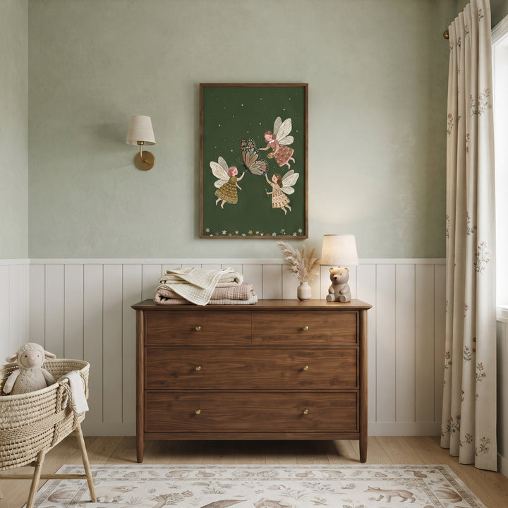 Wood dresser and monarch butterfly artist fairies wall art in a sage nursery. Includes a wicker bassinet and patterned rug.