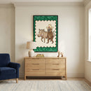 Framed drawing of a dressed-up baboon and warthog hanging above a wooden dresser in a neutral-toned living room, styled with a ceramic lamp, stacked books, and wooden animal toys.
