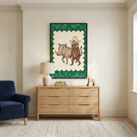 Framed drawing of a dressed-up baboon and warthog hanging above a wooden dresser in a neutral-toned living room, styled with a ceramic lamp, stacked books, and wooden animal toys.
