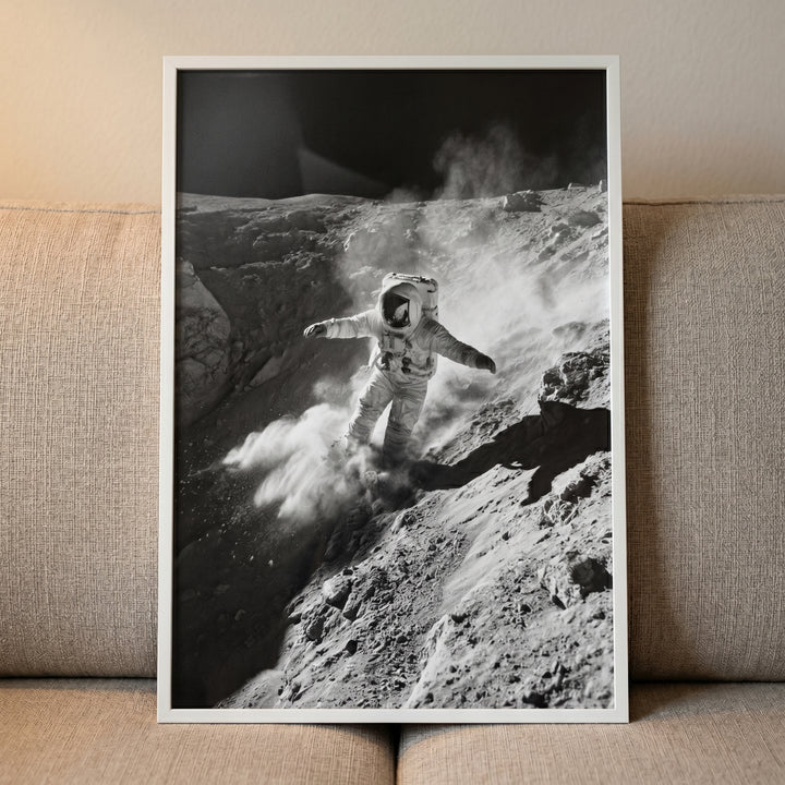 Monochrome crater dust astronaut wall art shows a figure in a spacesuit sliding down a steep, rocky lunar crater.