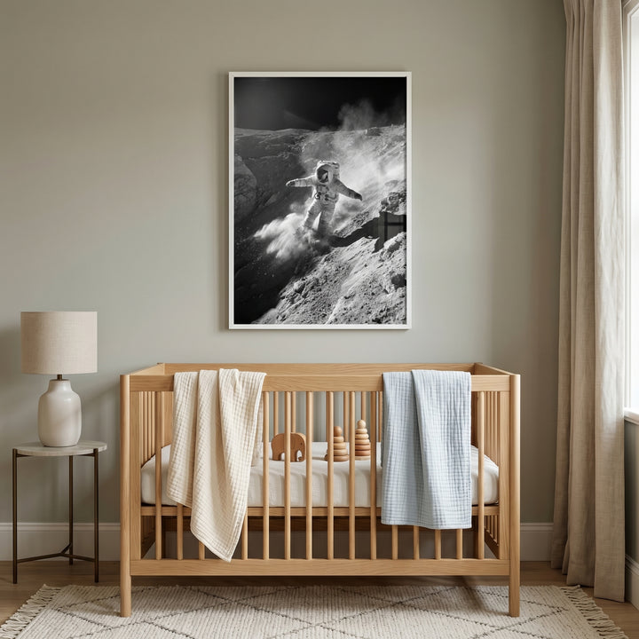 Wooden crib with blankets below monochrome crater dust astronaut wall art in a neutral nursery with a lamp and curtains.
