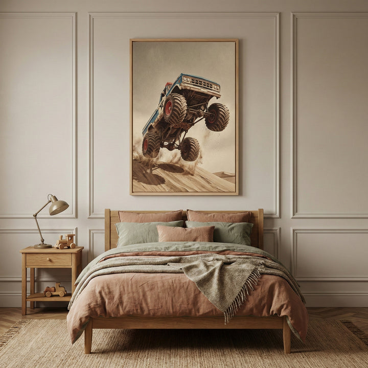 A grainy, vintage-style illustration of a blue and white monster truck soaring high in the air over a sand dune. The vehicle features massive, deeply treaded tires with red wheels, an elevated suspension, and a weathered body with a star emblem on the door. Dust and sand particles billow beneath the truck as it leaps from the crest of a sandy slope against a plain, desaturated background.
