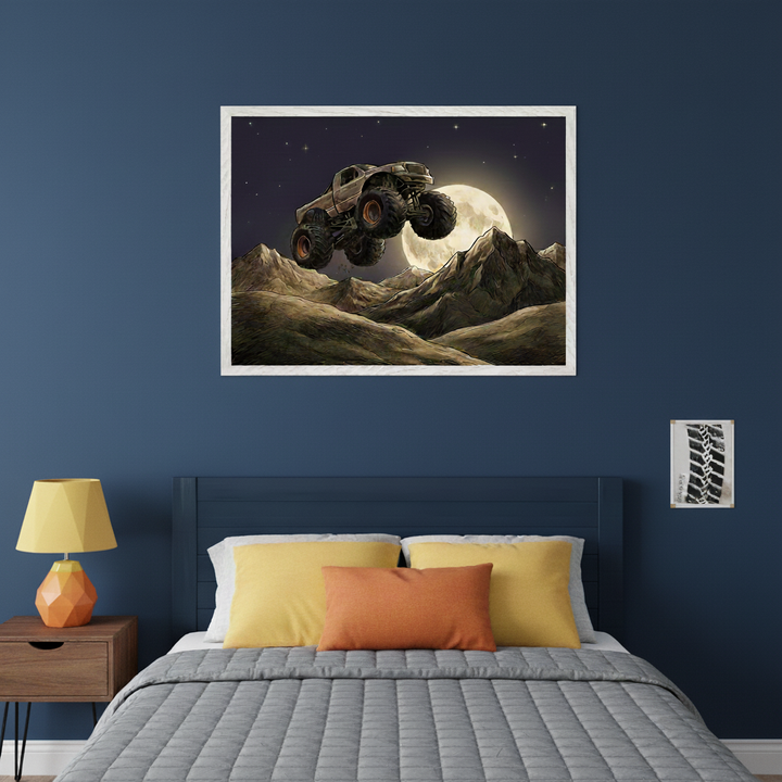 Kid's bedroom with a dark blue bed and headboard. A large framed illustration of a monster truck jumping over mountains with a full moon hangs centered above the bed. A smaller framed black and white tire tread print is on the wall to the right.