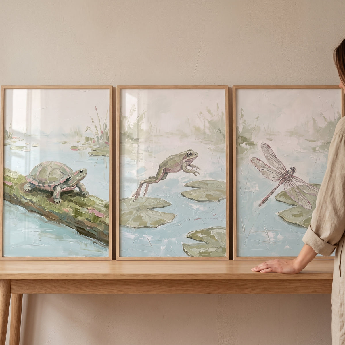Mossy sage pond animals wall art set of 3 featuring a turtle, frog, and dragonfly in wood frames on a table.