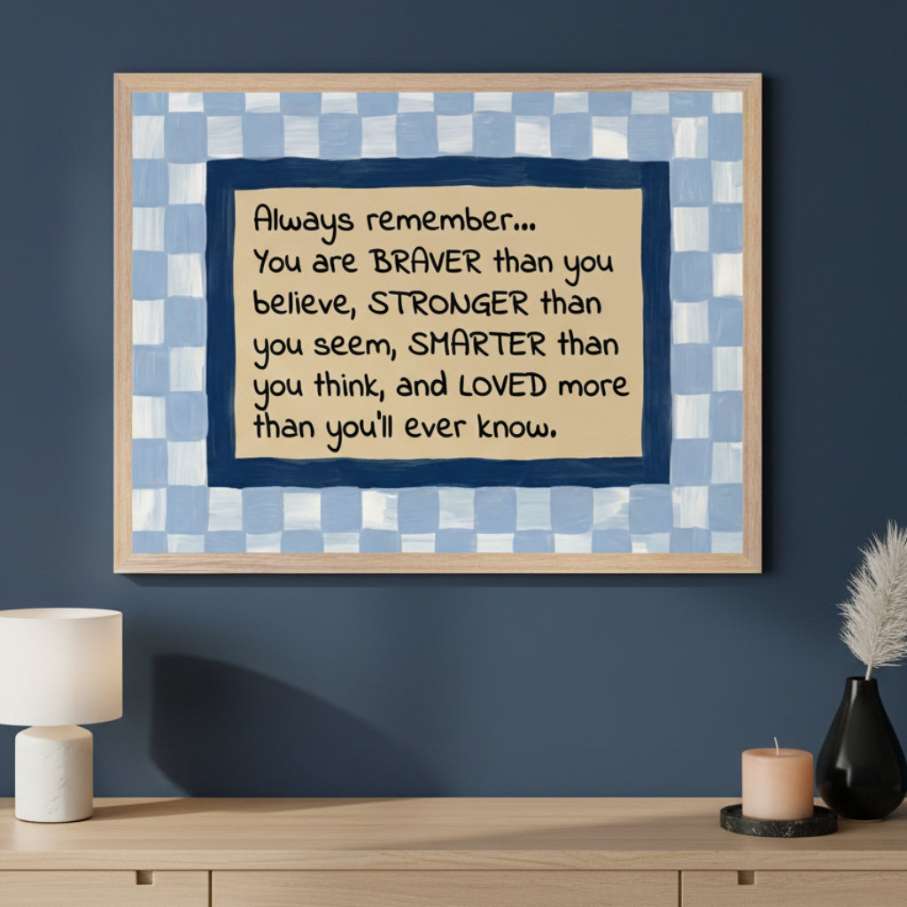 Modern room with a light wood dresser. A framed motivational quote art hangs centered above it. The art features a hand-drawn checkerboard frame in light and dark blue around a beige background with an encouraging message about being brave, strong, smart, and loved.