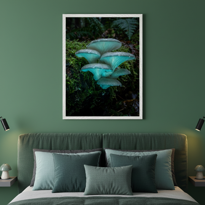 Bedroom with a green upholstered bed, green pillows, and two floating bedside tables with mushroom lamps. A large framed photograph of glowing blue-green mushrooms on a mossy log hangs centered above the bed.