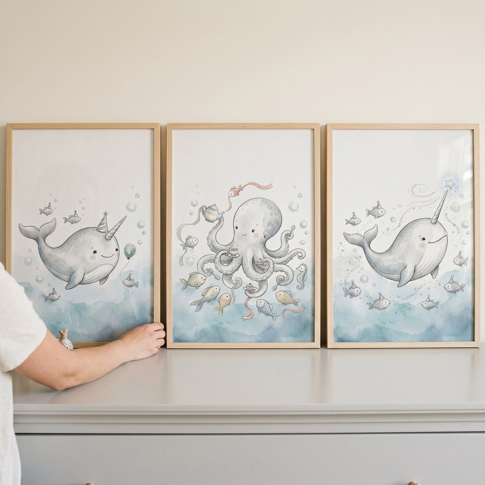 Muted blue sea creature wall art set of 3 featuring a narwhal with a hat, an octopus with tea, and a narwhal with a wand.