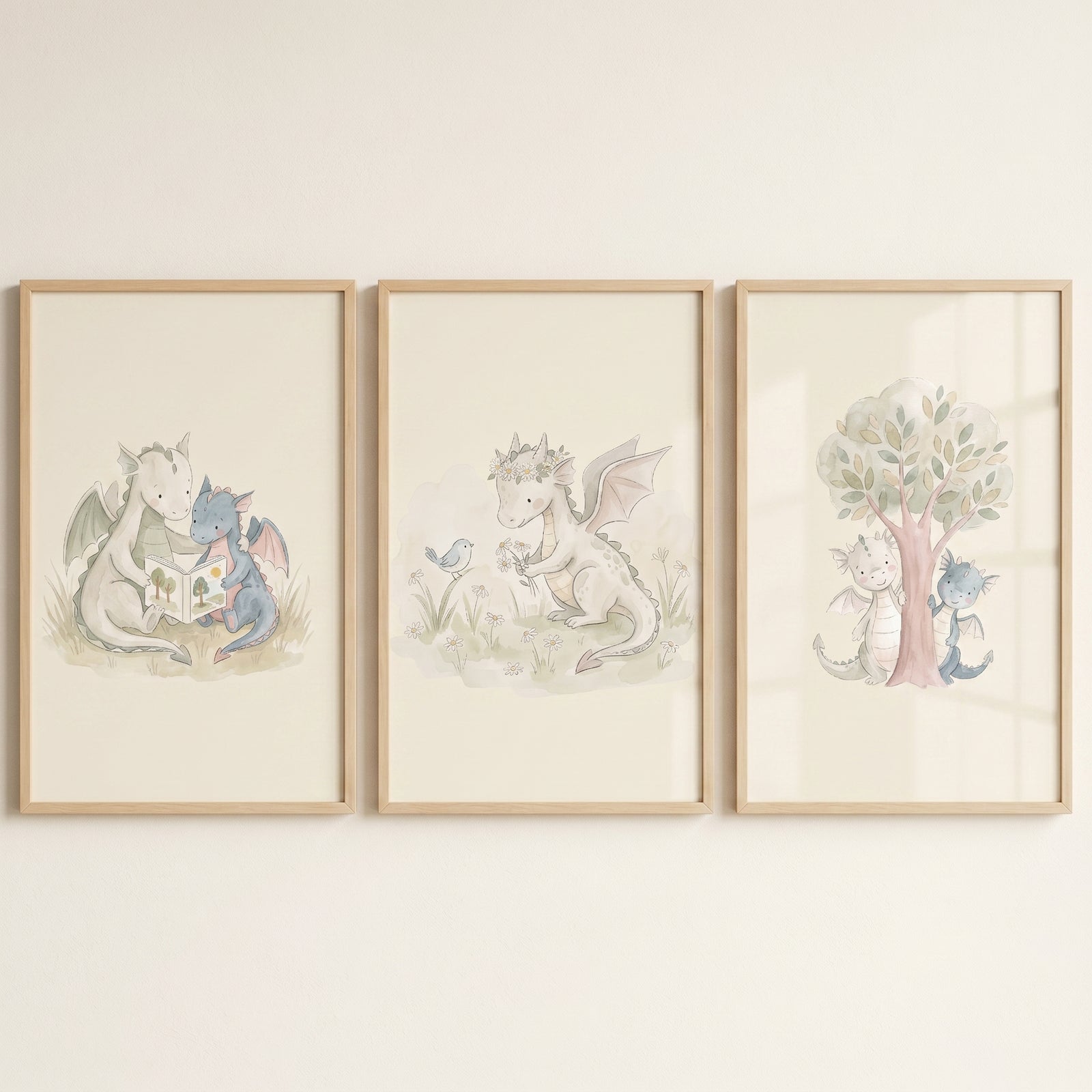Muted cream baby dragons wall art set of 3 in wood frames depicting dragons reading, playing with a bird, and by a tree.
