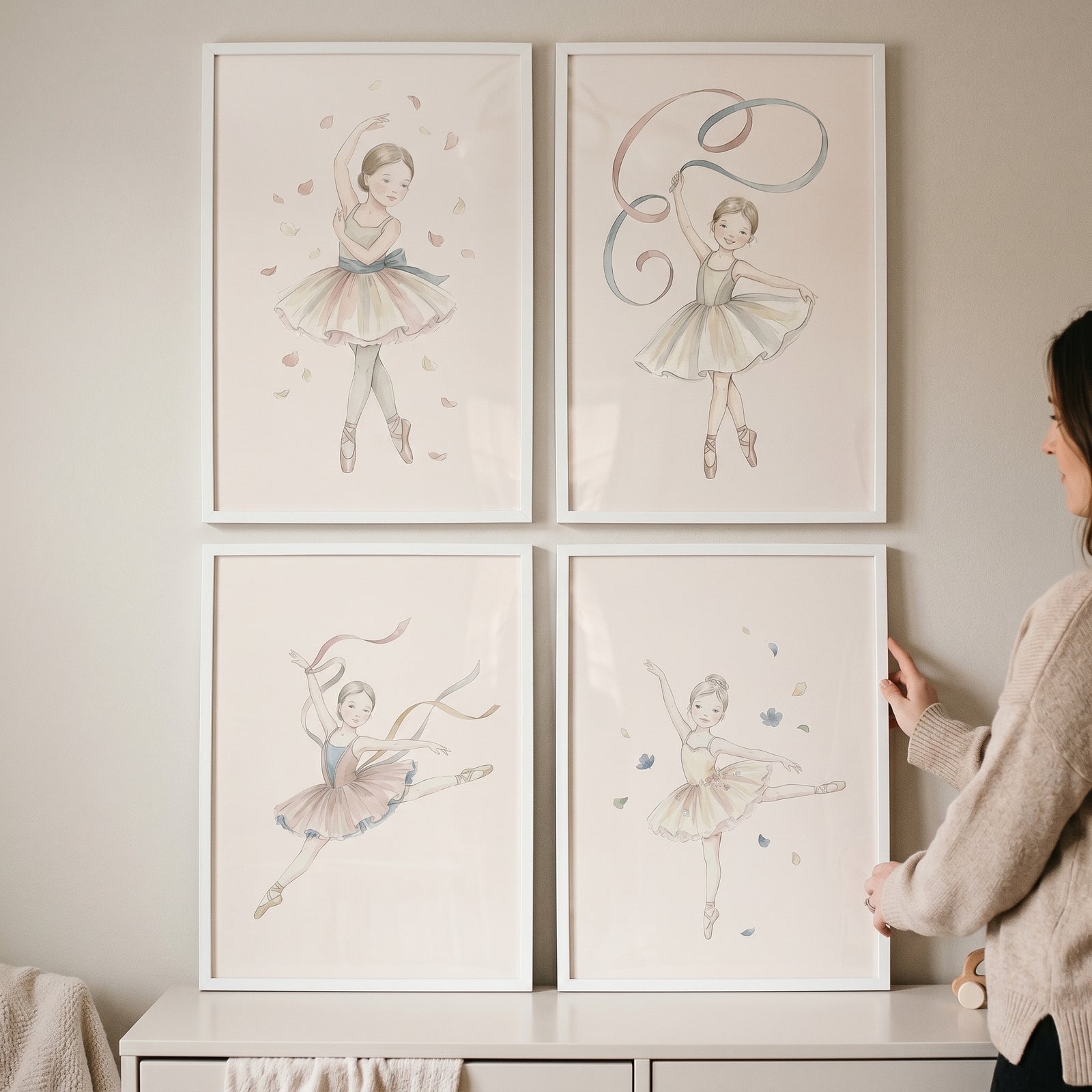 Muted cream tutu ballerina wall art set of 4 in white frames hangs on a wall as a woman positions the bottom right frame.