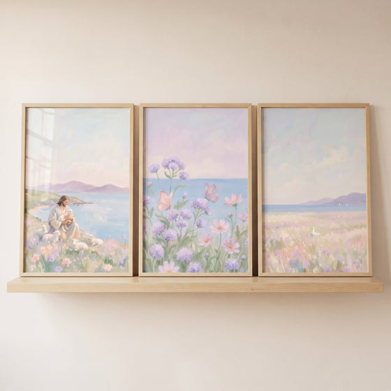 Jesus with lambs and butterflies in a muted lavender meadow coastal wall art set of 3 displayed on a wooden shelf.
