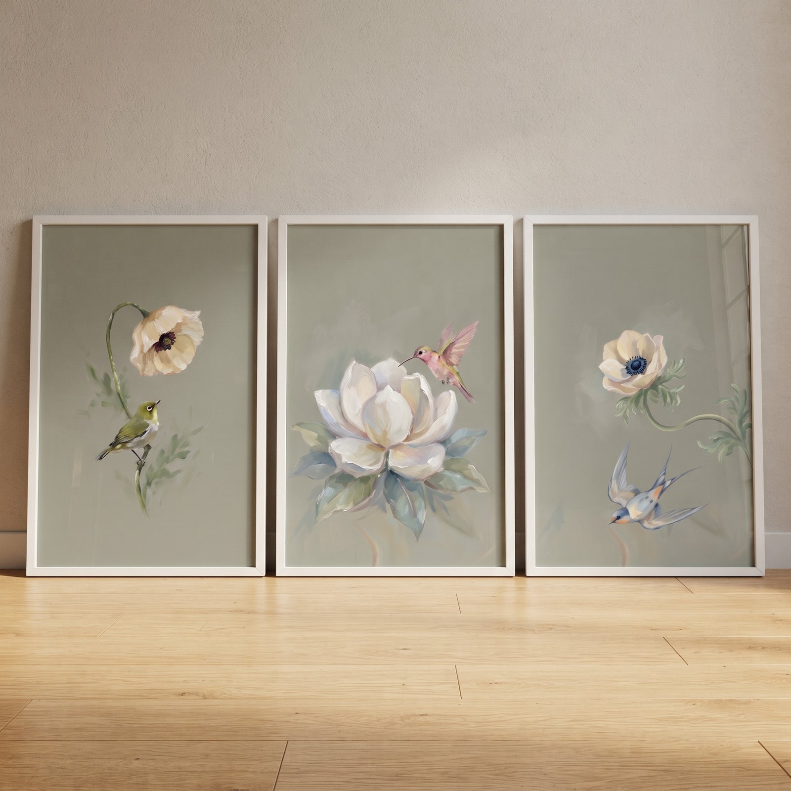 Muted palette garden bird artwork set of 3 displays birds and flowers in white frames on a wooden floor.