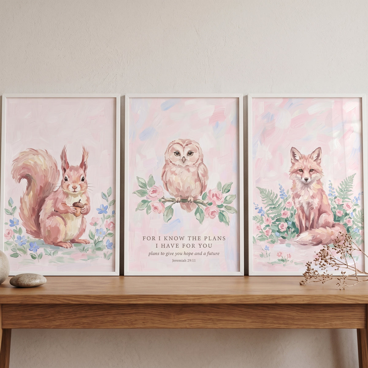 Muted rose woodland animals wall art set of 3 featuring a squirrel, owl with scripture, and fox on a wooden table.