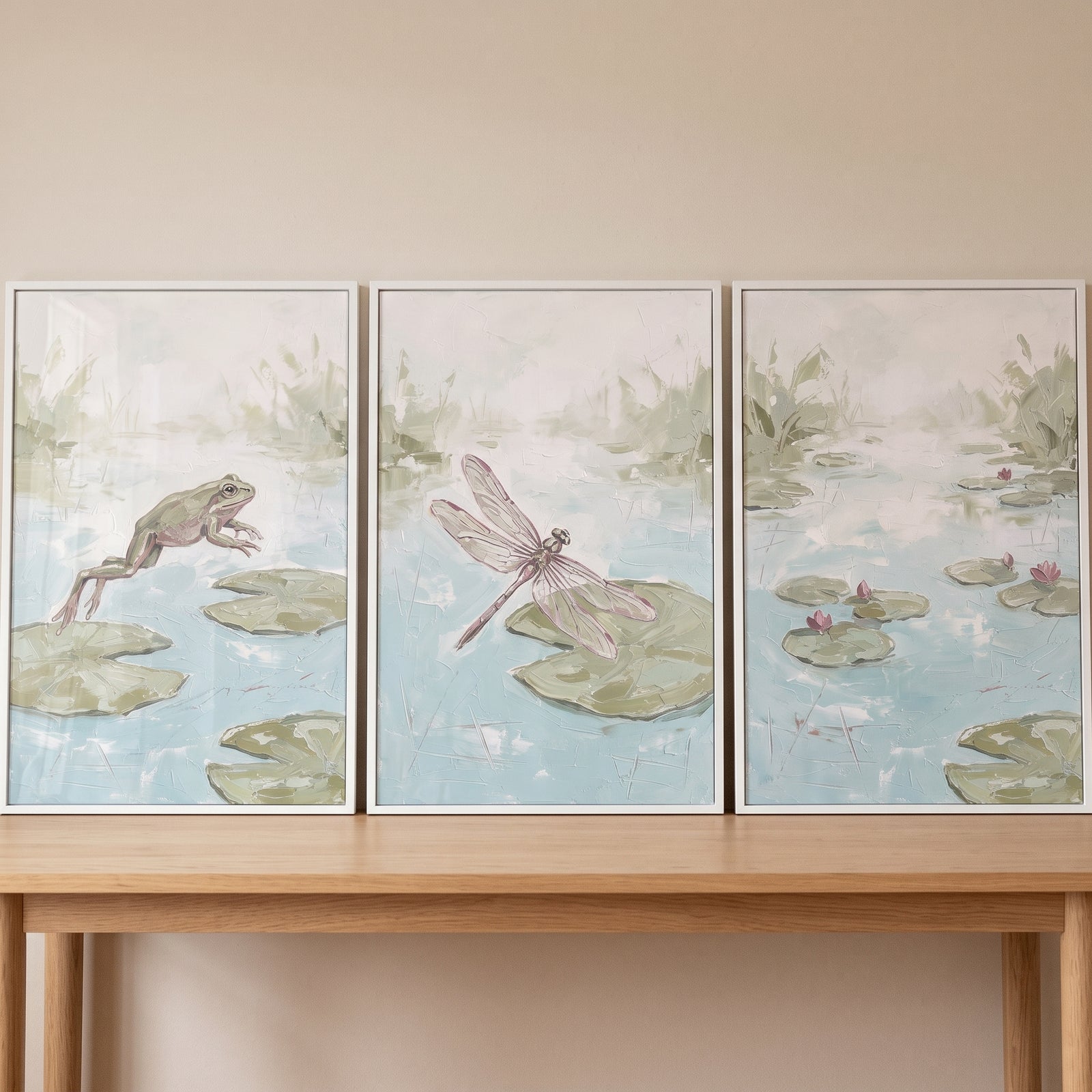 Muted sage lily pond wall art set of 3 with a frog, dragonfly, and water lilies displayed on a wooden console table.