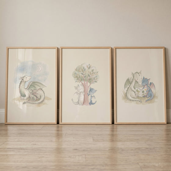 Muted sage mythical dragons wall art set of 3 in wood frames features dragons reading, by a tree, and with a moon.