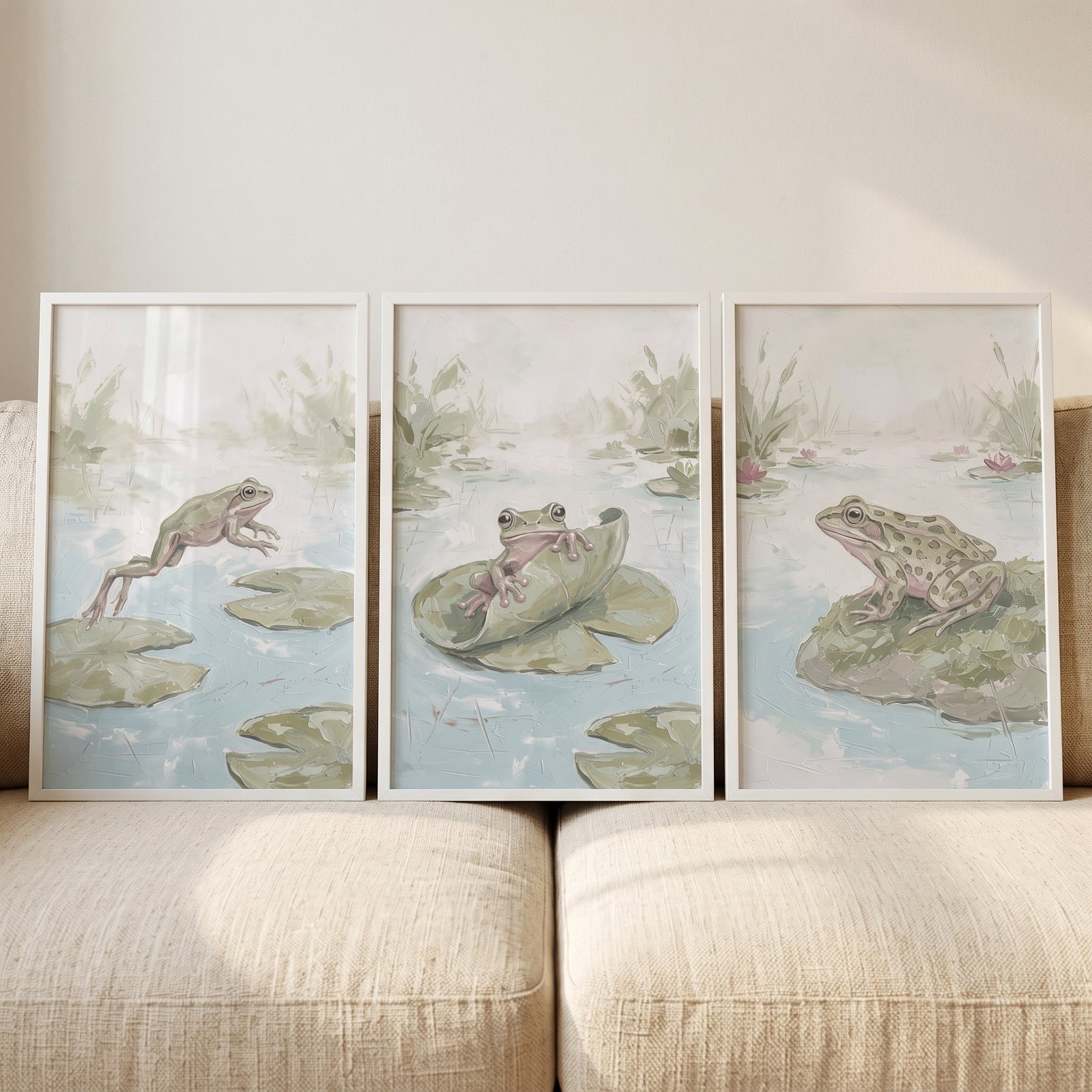 Muted sage pond animals wall art set of 3 featuring three framed frog prints in soft tones on a beige sofa.