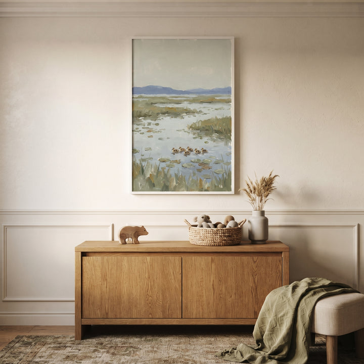 Muted sage swimming duckling wall art above a wood cabinet with a toy basket and bear figurine in a neutral room.