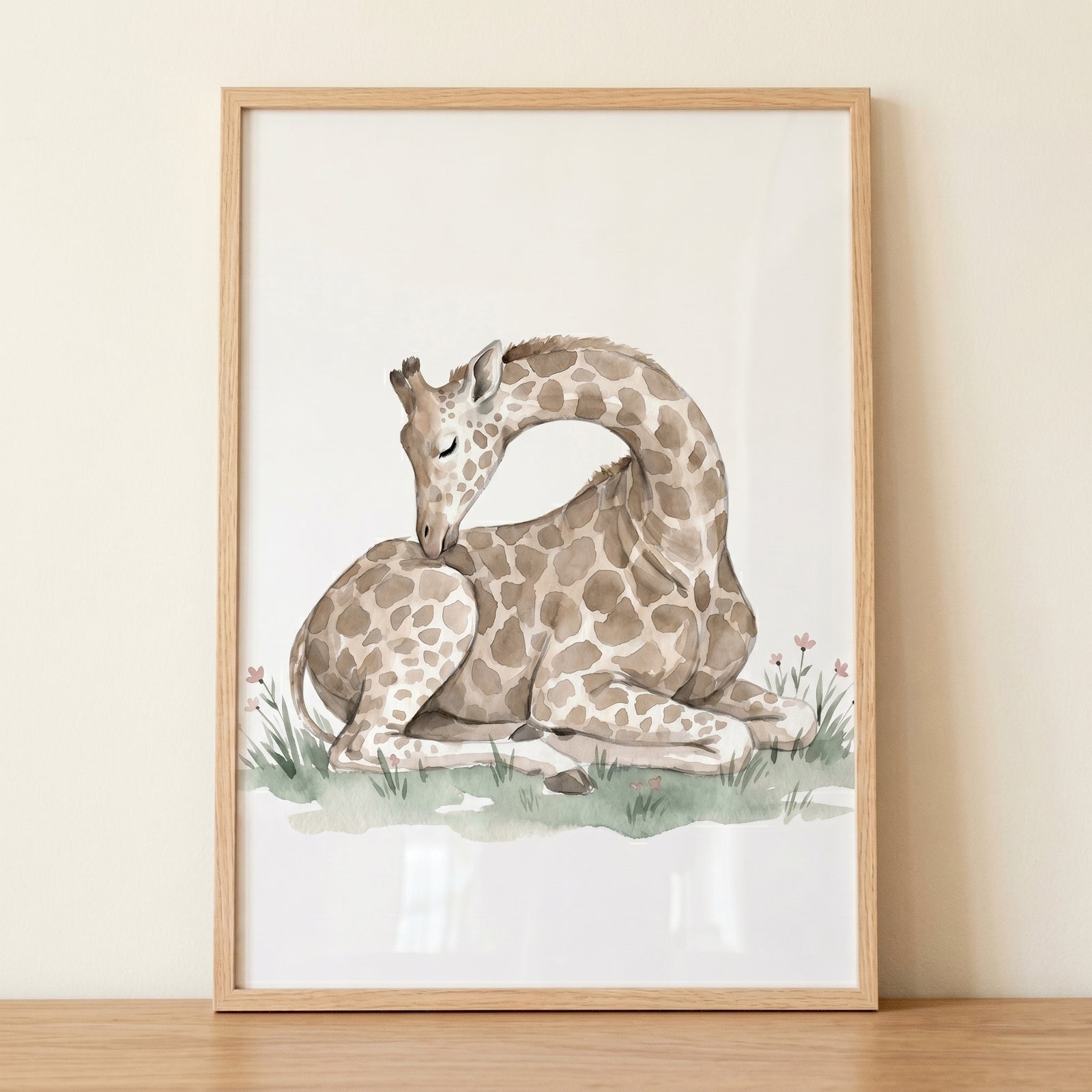 Muted tone resting giraffe artwork in a wood frame, featuring a watercolor animal in grass with small pink flowers.