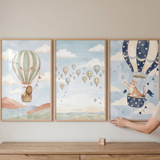 Muted watercolor air balloon wall art set of 3 featuring a lion, a tiger, and several balloons in a soft blue sky.