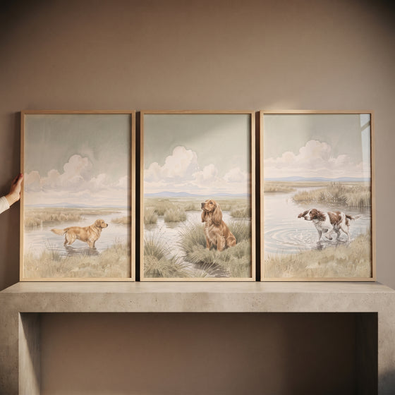 Muted watercolor hunting dog wall art set of 3 depicts dogs in misty wetland landscapes within light wood frames.
