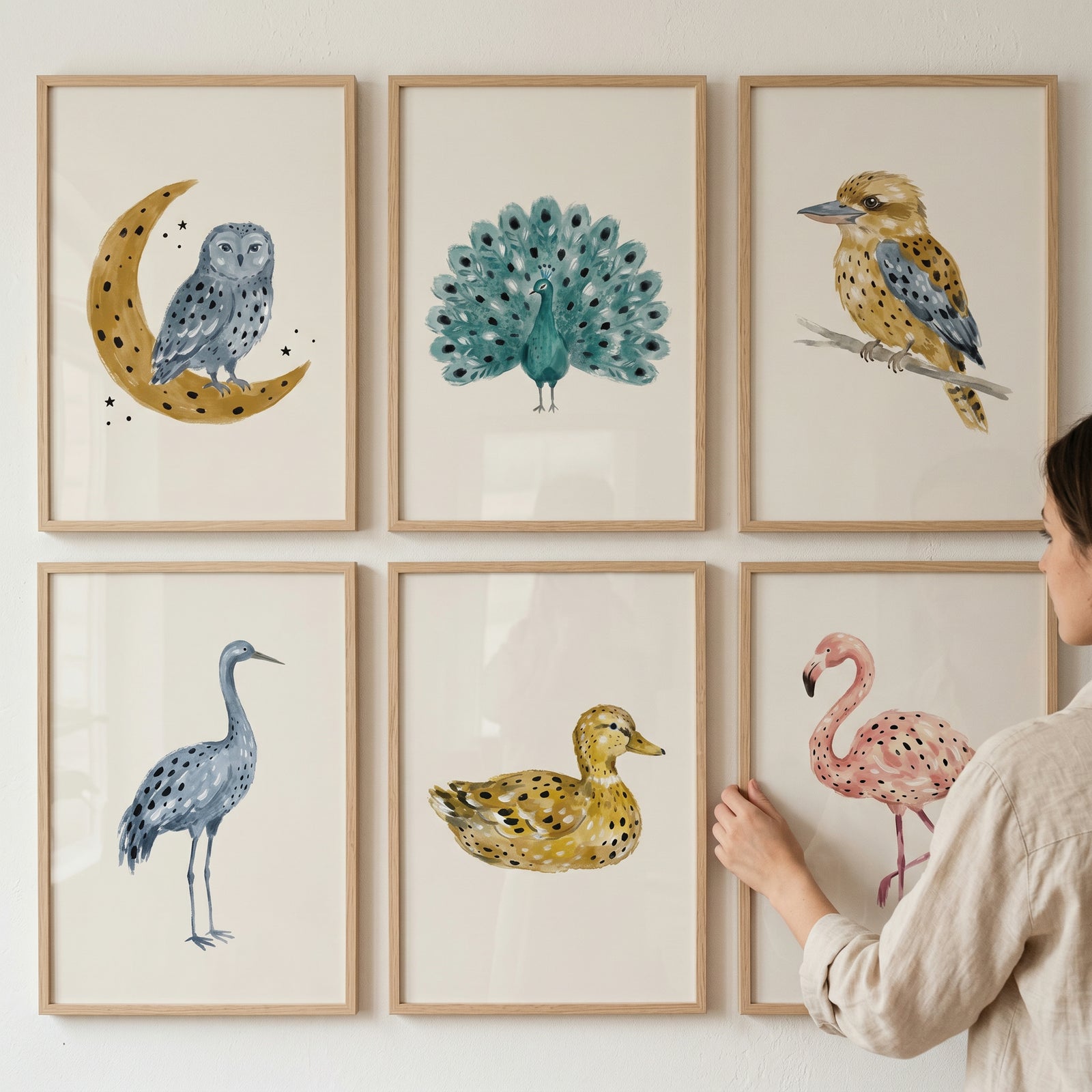 Muted watercolor spotted birds wall art set of 6 featuring an owl, peacock, and flamingo being hung on a white wall.