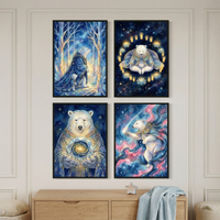 Four rectangular artworks featuring mystical polar bears in cosmic themes. Top left: a bear in a star-patterned robe walks with a cub through a wintry forest. Top right: a bear meditates in a blue garment surrounded by glowing candles. Bottom left: a bear holds a swirling galaxy orb. Bottom right: a bear in a cape reaches for a celestial light. The black frames hang on a neutral wall above a wood dresser with a blue textured cloth and a star-shaped decorative object.