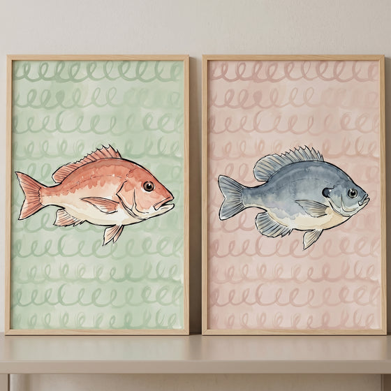 Nautical theme watercolor fish wall art set of 2 featuring red and blue fish over green and pink wave patterns.