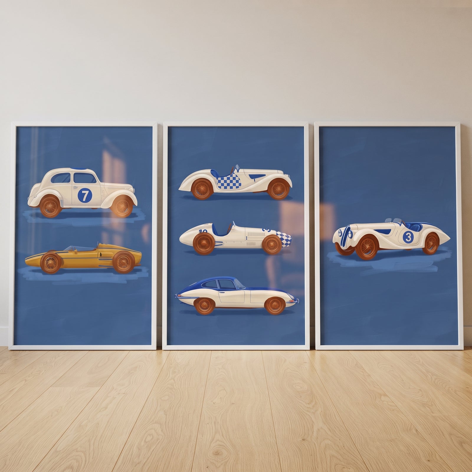 Navy blue racing car wall art set of 3 featuring vintage race cars in white frames resting on a light wood floor.