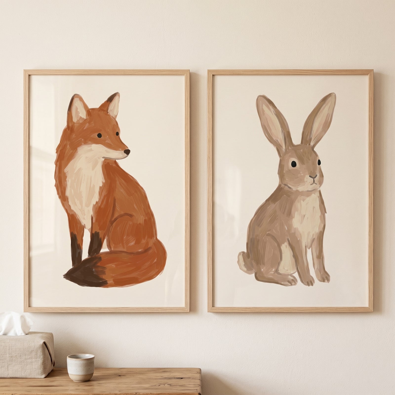Neutral brushstroke woodland animals wall art set of 2 with a fox and a rabbit in light wood frames on a wall.