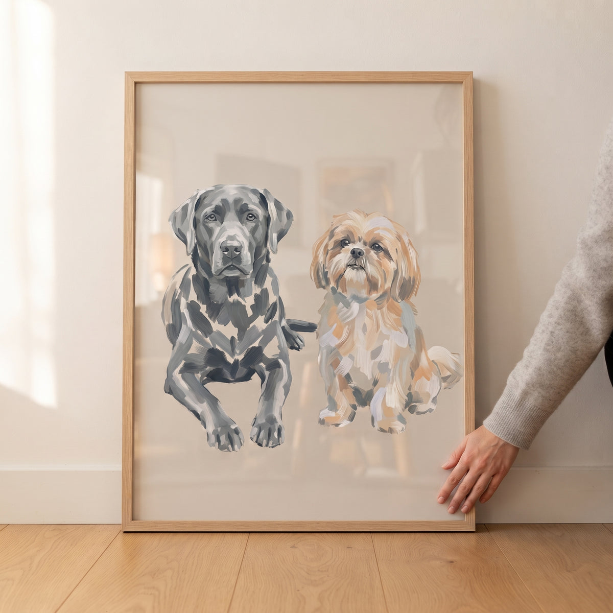 Hand touches neutral labrador shih tzu wall art in a wood frame featuring a black lab and a tan shih tzu.