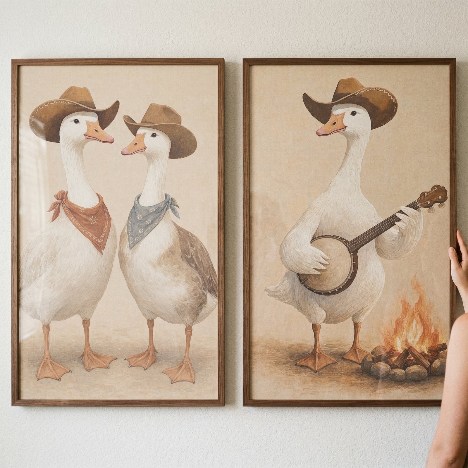 Neutral minimalist cowboy goose wall art set of 2 features geese in hats and bandanas, and one playing banjo by a campfire.