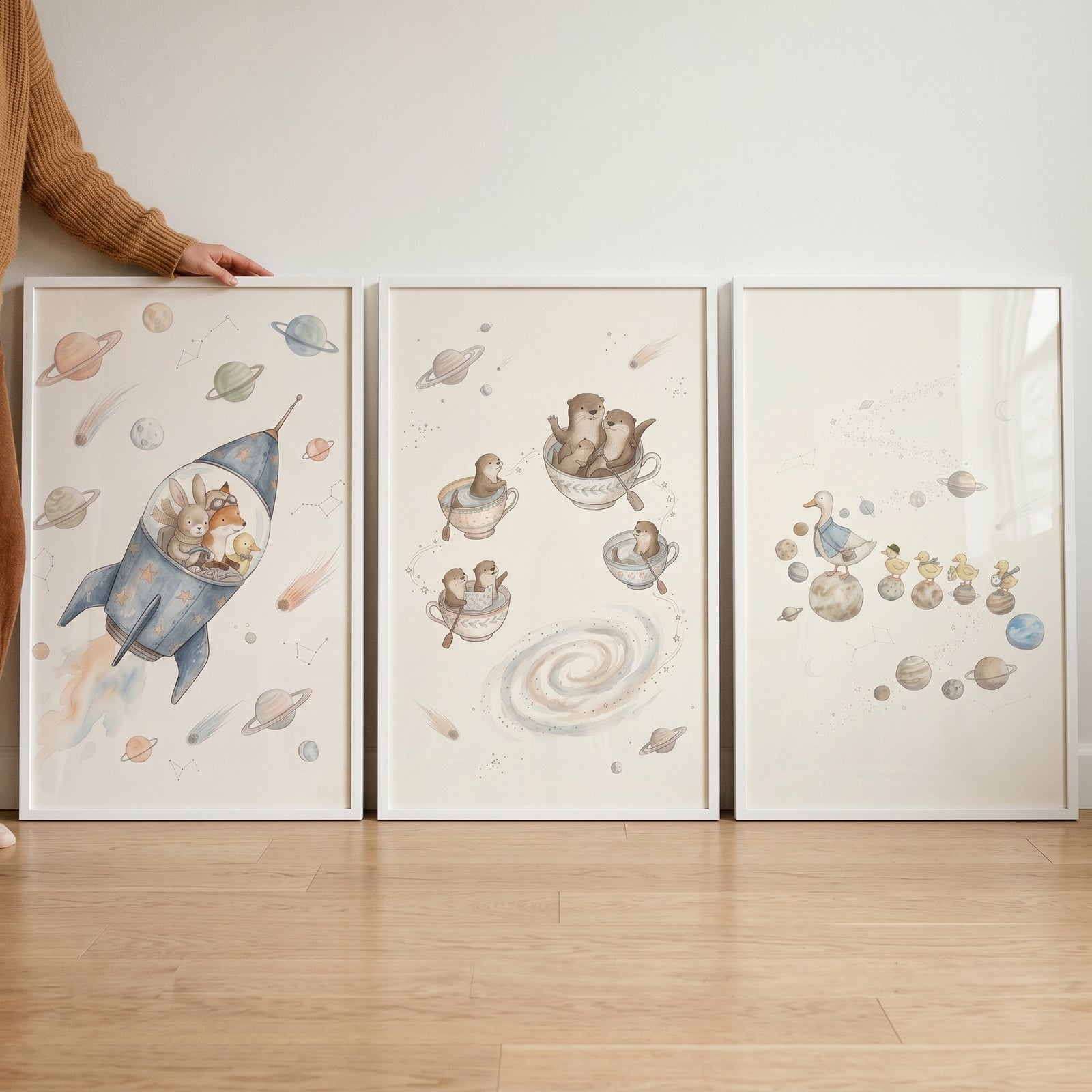 Watercolor neutral nursery space animals wall art set of 3 featuring a rocket, otters in teacups, and ducks on planets.