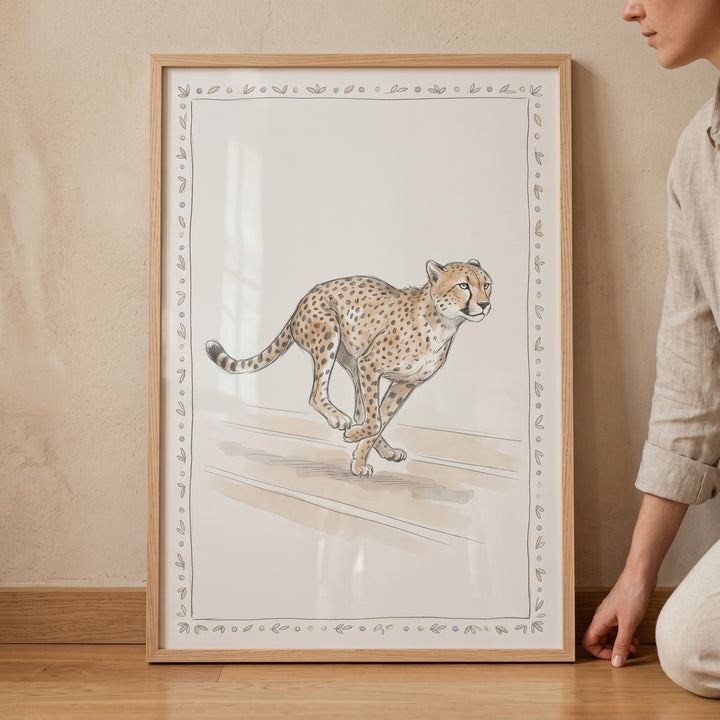 Neutral running cheetah artwork in a light wooden frame leaning against a wall next to a person.