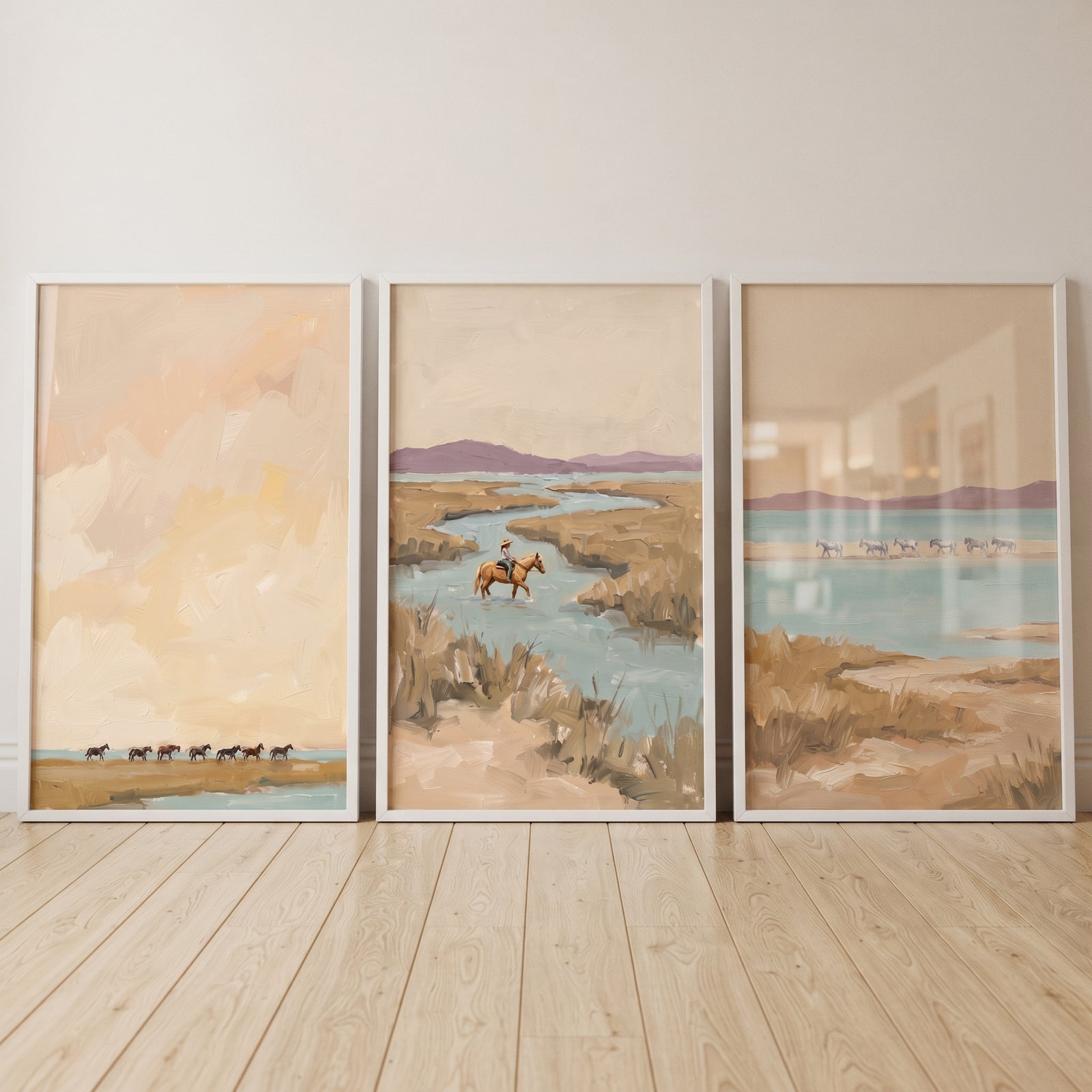 Neutral textured coastal horses wall art set of 3 in white frames showing horses by the water in soft tan and blue tones.