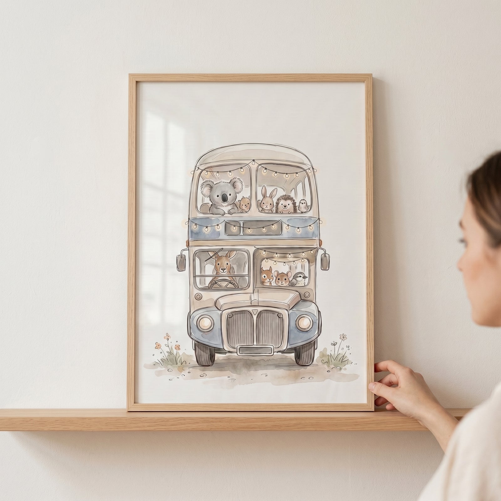 Neutral toned animal bus wall art in a wood frame on a shelf features various cute animals on a vintage double-decker bus.