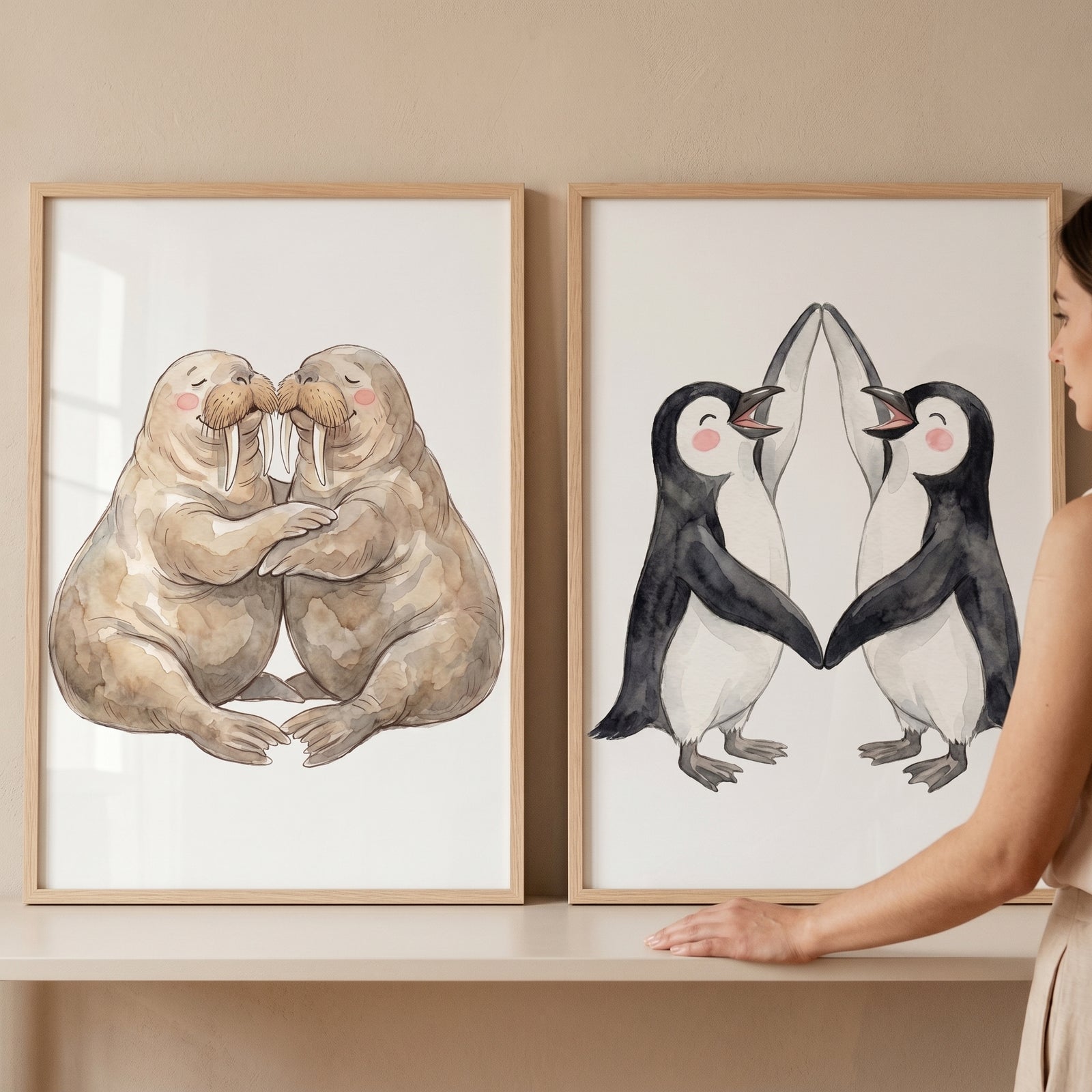 Neutral watercolor arctic animal wall art set of 2 featuring hugging walruses and high-fiving penguins in wood frames.