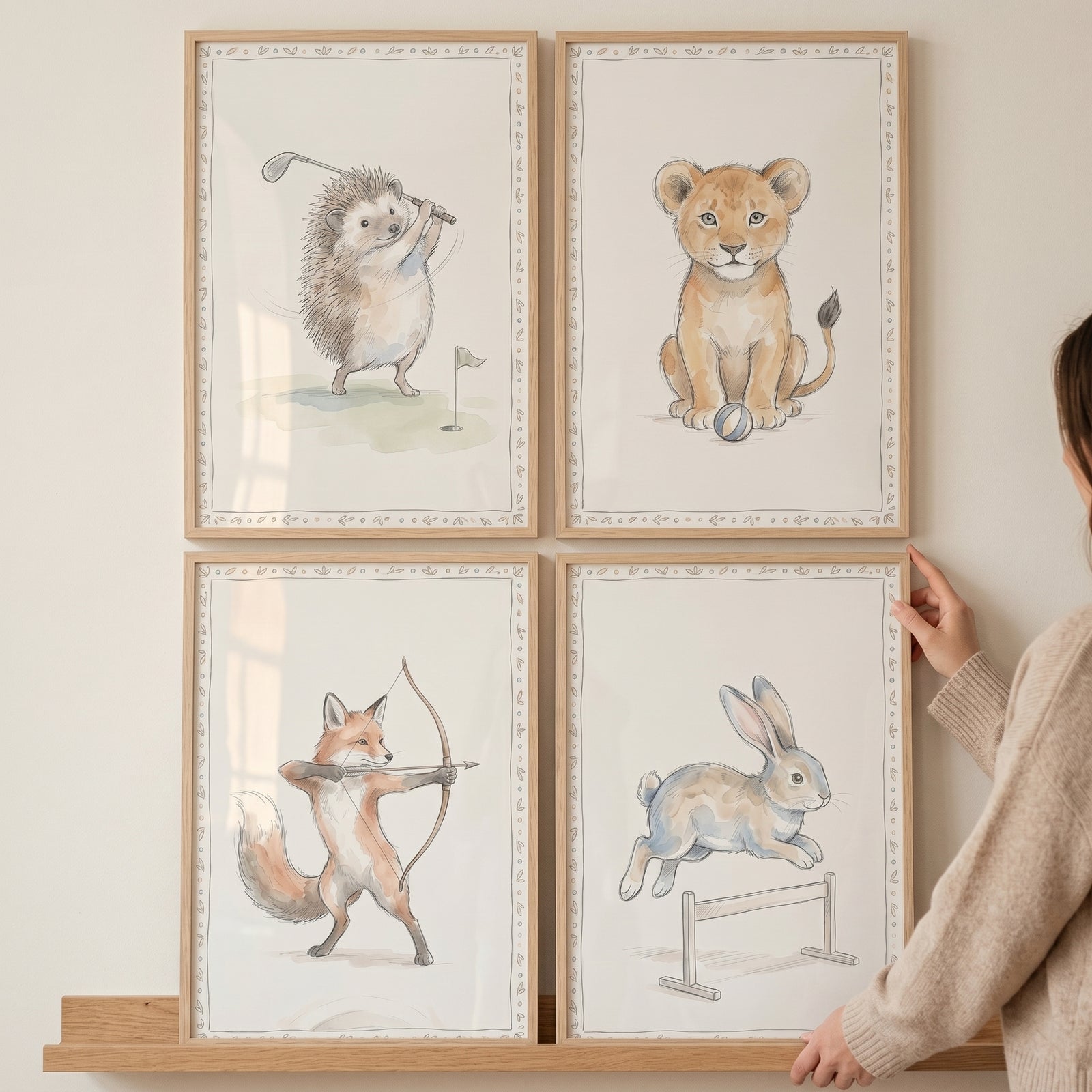 Neutral watercolor athletic animal wall art set of 4 shows a golfing hedgehog, lion cub, archery fox, and jumping rabbit.