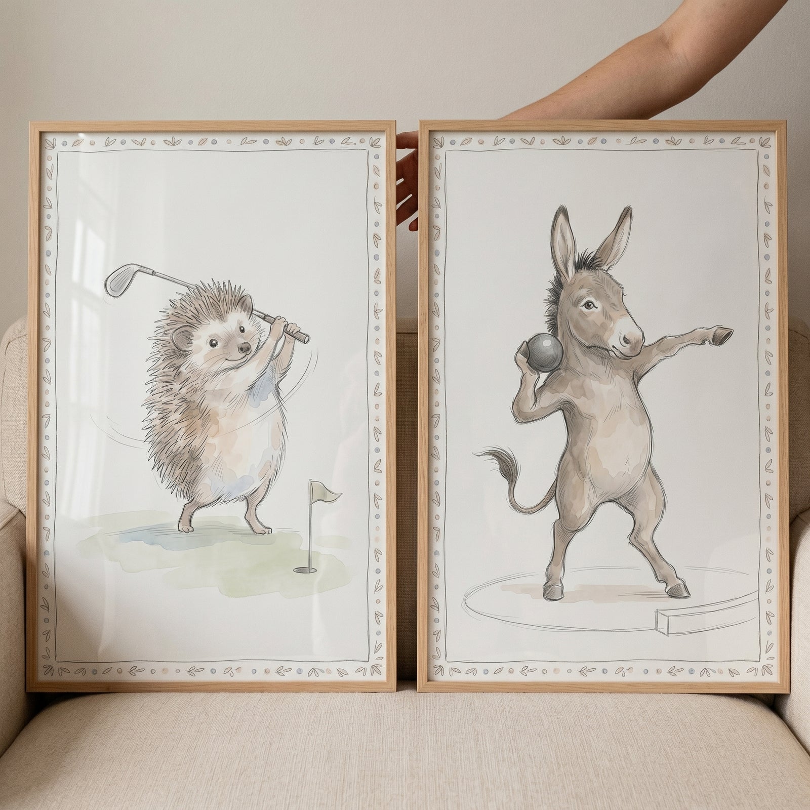 Neutral watercolor athletic animals wall art set of 2 with a hedgehog playing golf and a donkey throwing a shot put.