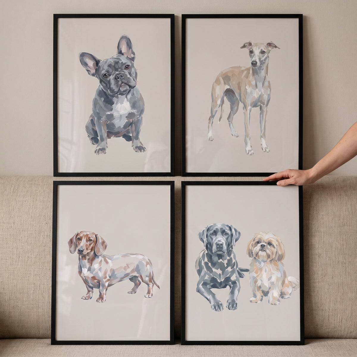 Neutral watercolor multi dog wall art set of 4 featuring various breeds in black frames with a hand holding one.