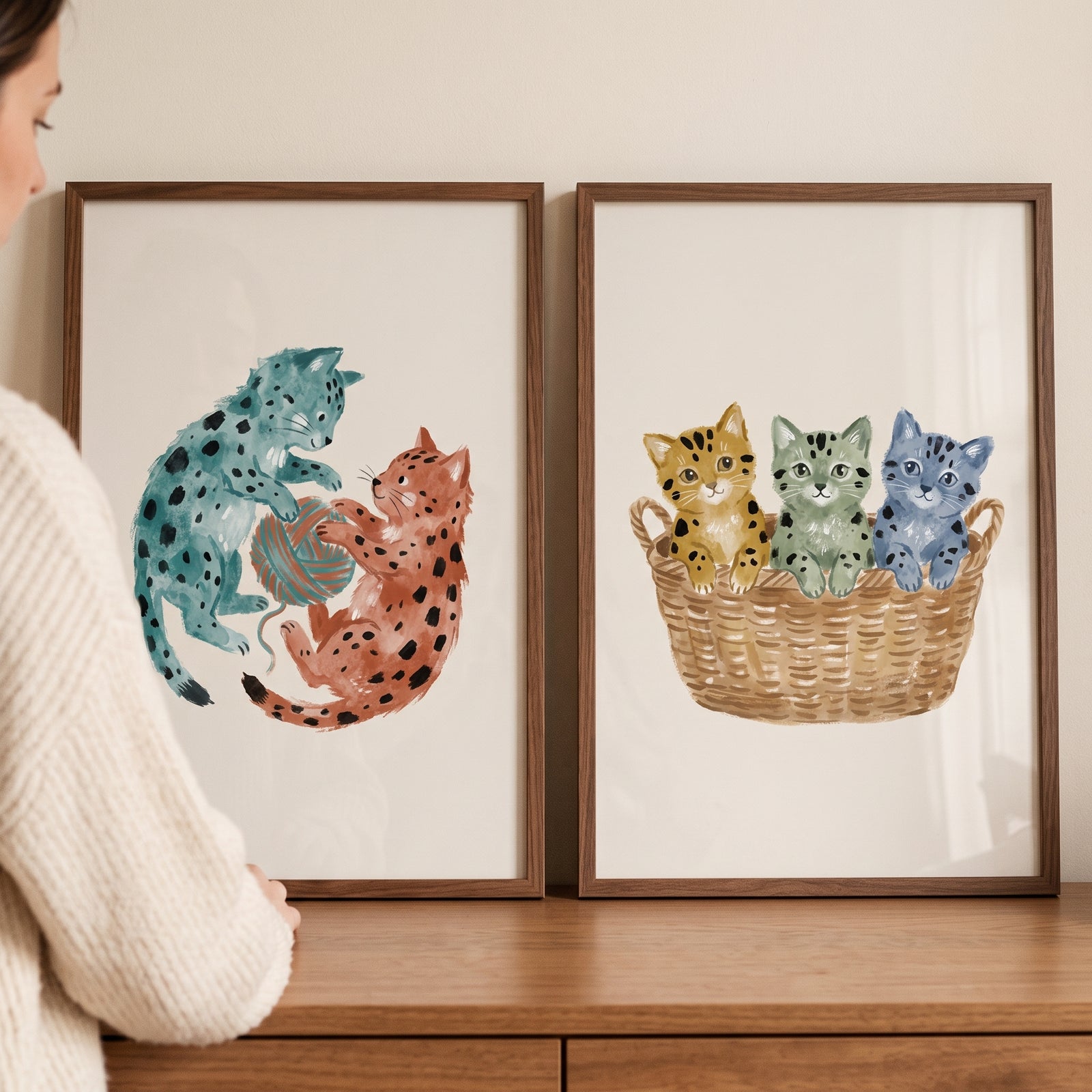 Neutral watercolor spotted cat wall art set of 2 featuring colorful felines playing with yarn and sitting in a basket.